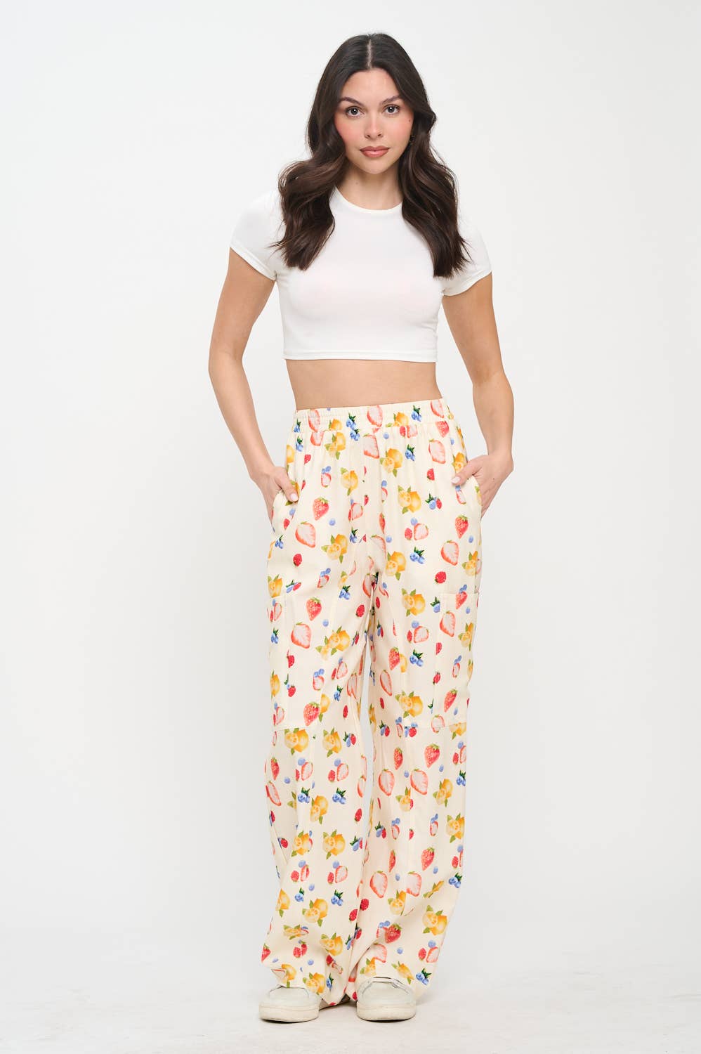 Full-body shot of a model wearing berry print wide-leg pants with a white crop top and sneakers, highlighting the relaxed fit and stylish design
