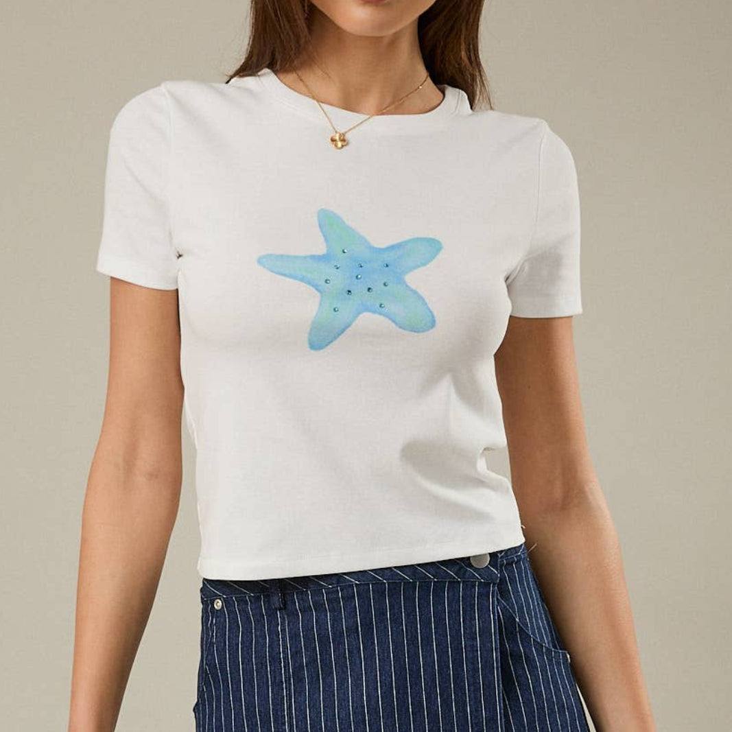 Woman wearing a white t-shirt with a blue starfish design and a navy pinstripe skirt on a beige background