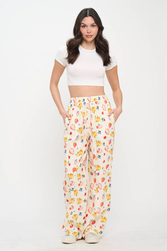 Full-body shot of a model wearing berry print  wide-leg pants with a white crop top and sneakers, highlighting the relaxed fit and stylish design