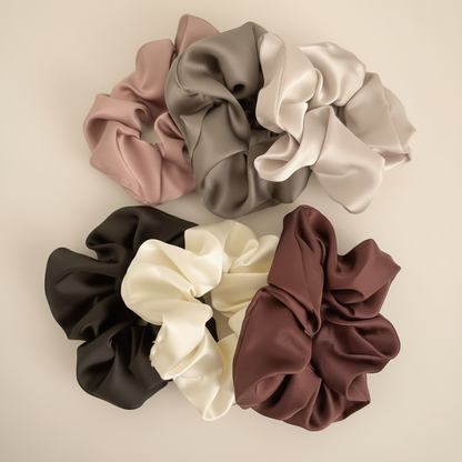 Set of six satin scrunchies in various colors on a light gray background.