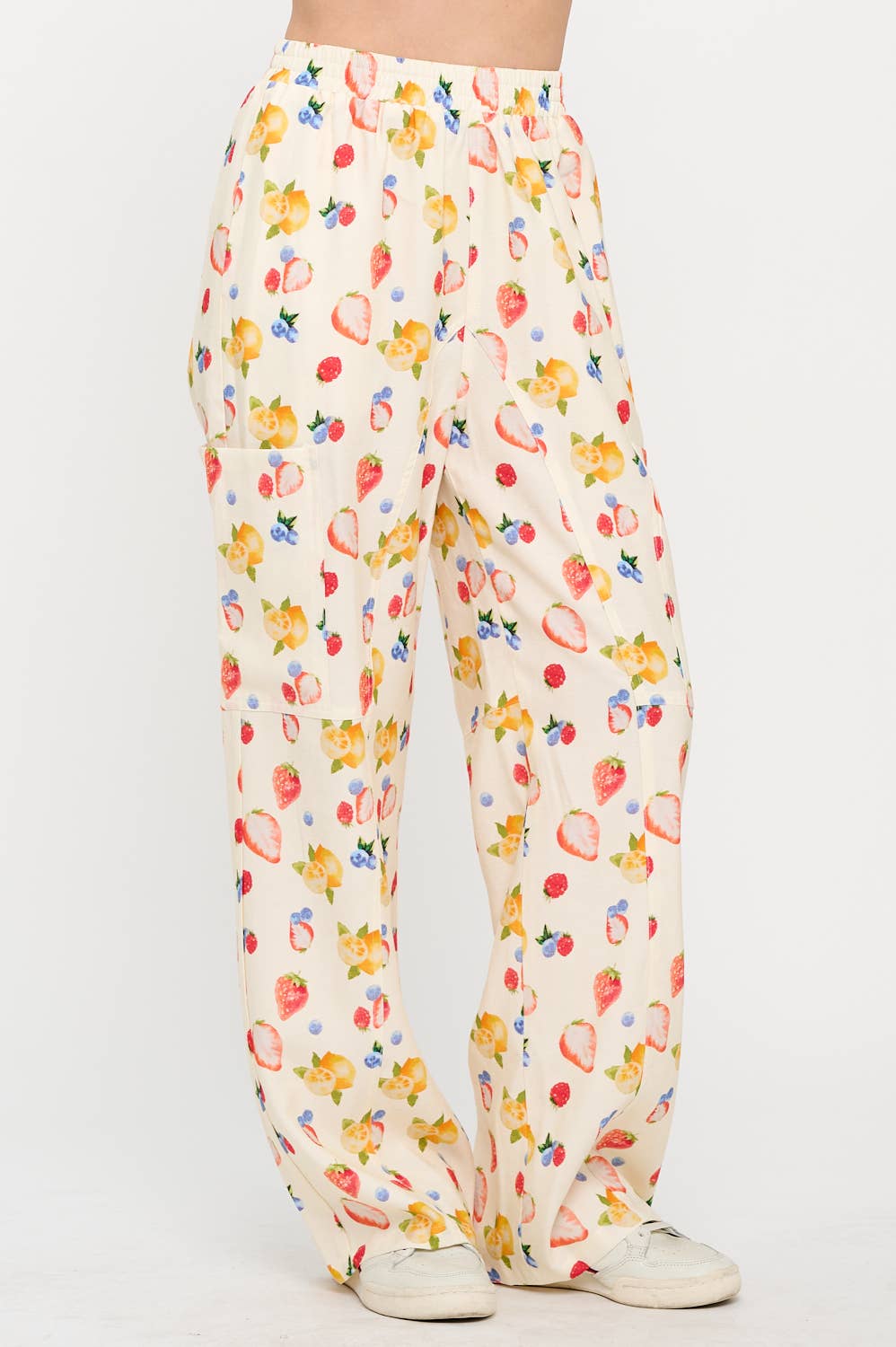 Angled side view of berry wide-leg pants, showing the vibrant fruit pattern and relaxed fit, styled casually with sneakers for a laid-back vibe.
