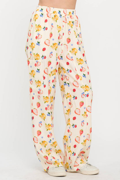 Angled side view of berry wide-leg pants, showing the vibrant fruit pattern and relaxed fit, styled casually with sneakers for a laid-back vibe.